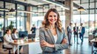 © engincan - Successful, happy businesswoman smiling confidently in a modern office environment, representing teamwork, collaboration, and career success.