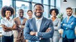 © engincan - Successful African American CEO leading diverse team in modern office, confident businessman with folded hands overseeing joyful professional group
