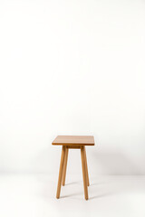 Poster - Simple wooden table stands alone against a plain white background of an exposed brick wall._00002_