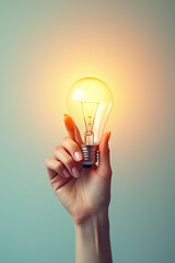 Aufkleber - Female hand holds a glowing lightbulb on a soft pastel colored background, symbolizing creative ideas and innovative thoughts emerging._00001_