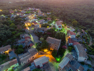 Wall Mural - Aerial view of a charming village at dusk, nestled amidst lush greenery.