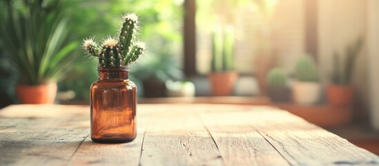 Poster - Cactus in a brown glass bottle on wooden table with blurred greenery providing interior decoration inspiration for modern spaces