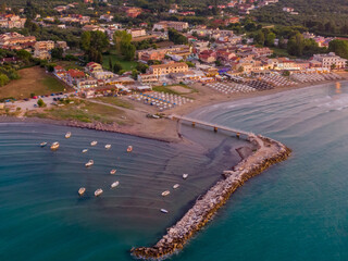 Wall Mural - Aerial view of coastal town with pier, boats, and beach at sunset.