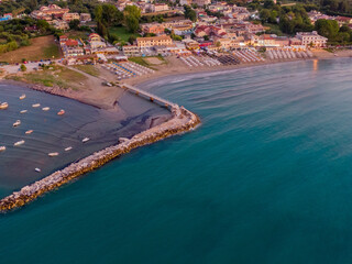 Wall Mural - Aerial view of coastal town with beach, pier, and boats at dusk.