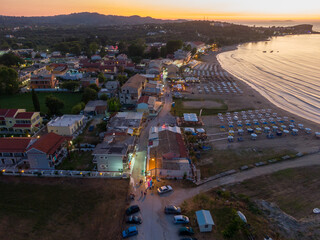 Wall Mural - Aerial sunset view of a coastal town with beach, buildings, and cars.