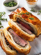 © ~ LENA BUKOVSKY ~ - Delicious beef pastries with thyme displayed on a clean white plate, highlighting their appetizing appearance. Beef Wellington special dinner for Valentine’s Day, Anniversary or candlelight dinner.