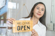 © Pormezz - Small business owner smiling while turning the sign for open store.