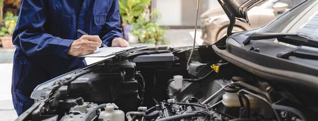 Wall Mural - Auto check up and car service shop concept. Mechanic writing job checklist to clipboard to estimate repair quotation to client at workshop garage.