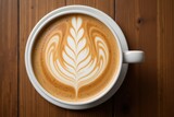 Artistic latte with intricate foam design in white cup on wooden table