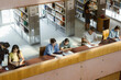© Maskot - High angle view of multiracial male and female college students studying in university library