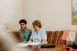 © Maskot - Smiling male nurse using laptop while sitting with senior woman on sofa at home