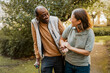 © Maskot - Smiling senior male holding hands of female nurse and walking at park