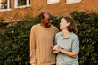 © Maskot - Smiling female nurse and elderly male looking at each other while standing in front of plants