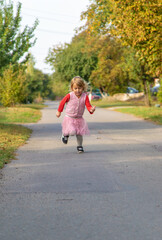 Poster - A child runs and jumps on the street along the road. Selective focus.