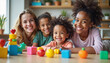 © Elenba - A joyful woman and three happy children playing with colorful building blocks in a bright room