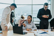 © qunica.com - A group of business people working together in a bright, modern office. They are engaged in a collaborative project using laptops and smart phones to communicate and plan effectively.