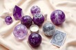 © Maryna - Purple crystal spheres, tarot card rest on soft beige fabric background. Small candle sits in center. Mystic objects for divination meditation, spiritual practices. Image evokes harmony, tranquility.