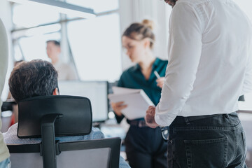 Wall Mural - A diverse group of employees are gathered in a bright, modern office space, engaged in a business meeting. The atmosphere is professional and focused on teamwork and collaboration.