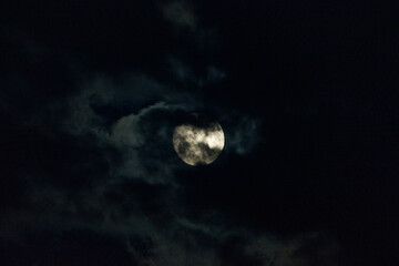 full moon partially obscured by clouds at night. a celestial sight.