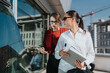 © qunica.com - Two business people engage in a discussion on a high-rise tower balcony. They are holding documents and pens, with city buildings visible in the background, illustrating a collaborative environment.