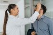 © qunica.com - A businesswoman helps her coworker by adjusting his glasses in an office environment. The casual and supportive interaction reflects teamwork and collaboration in a professional setting.