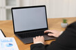 © New Africa - Businesswoman working with laptop at wooden table in office, closeup