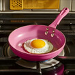 © jaxstre - an close up direct over head high resolution phito of a hot pink nonstick cookig pan with an egg in it on a stovetop from the 90s