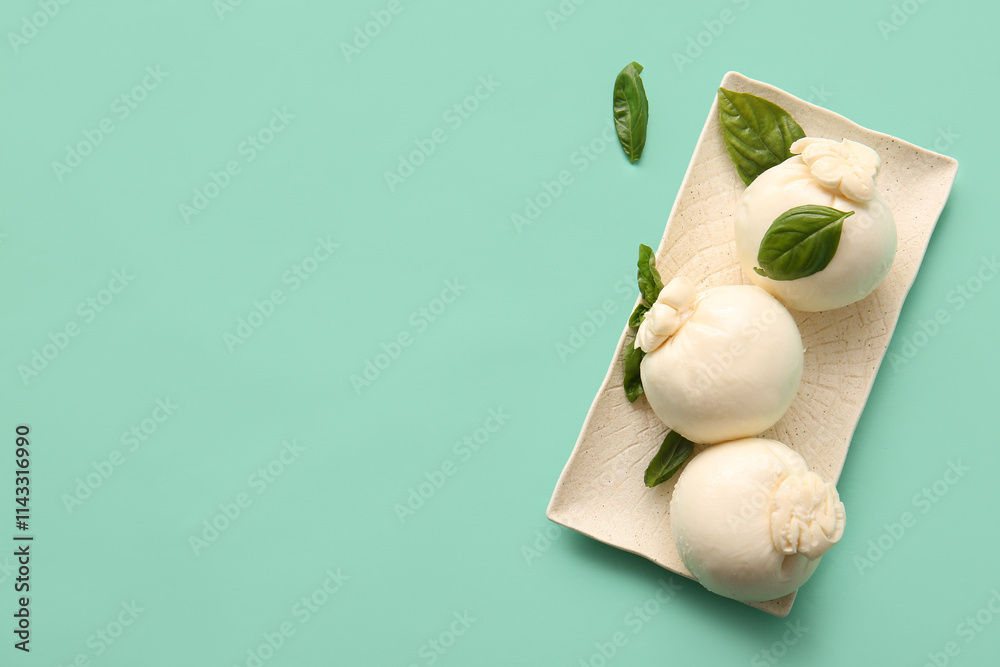 Plate of tasty Burrata cheese with basil on turquoise background