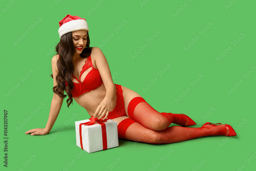 Beautiful young sexy woman in lingerie and Santa hat with gift box sitting on green background