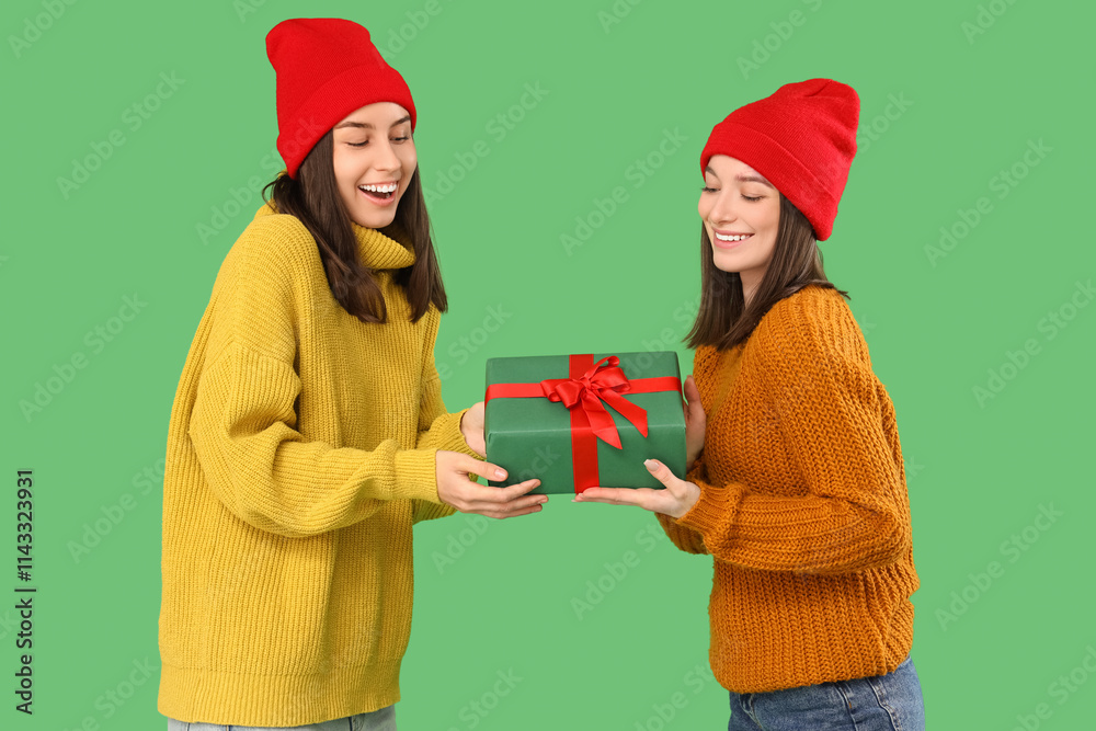 Young women with Christmas gift on green background