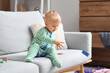 © Pixel-Shot - Cute baby boy throwing toy on sofa in messy room