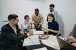 © qunica.com - A diverse group of business associates engages in a collaborative discussion, analyzing a project in a contemporary office setting. They are involved in a dynamic brainstorming session, sharing