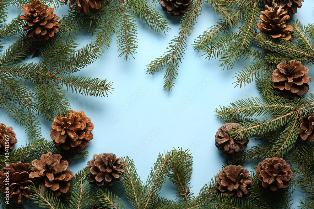 Frame made of pine cones and fir branches on blue background
