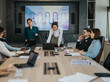 © qunica.com - A diverse group of business people engaging in a meeting, discussing strategies with a digital presentation. The scene is set in a modern conference room, emphasizing teamwork and communication.