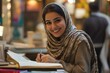 © Popelniushka - Joyful Middle Eastern Woman Writing Notes at Desk with Pen in Casual Attire