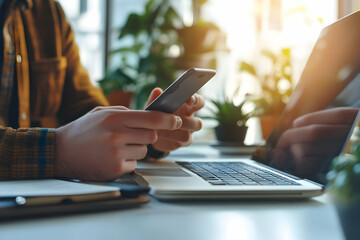 Poster - Close-up of hands holding phone, laptop and plants on desk.