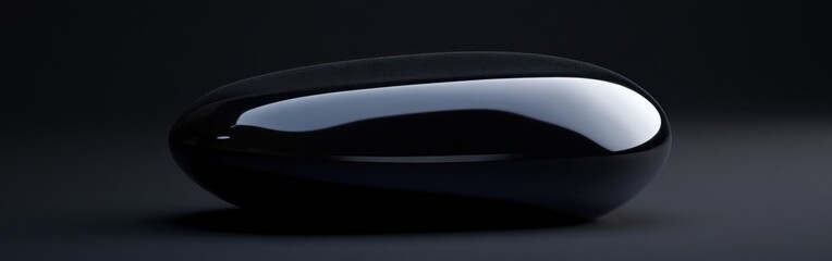 Poster - Obsidian stone displaying deep black color with smooth surface reflecting light in a minimalistic setting