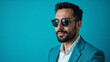 © InspirationDesign - Professional businessman in light blue blazer and sunglasses against turquoise background with confident expression