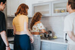 © qunica.com - A group of friends gather in a modern kitchen, enjoying time together while preparing a meal. Collaborative cooking and camaraderie are evident.