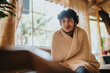 © qunica.com - A young man sits comfortably wrapped in a soft blanket, enjoying a relaxing moment indoors. The bright room and natural light create a warm, comforting atmosphere.