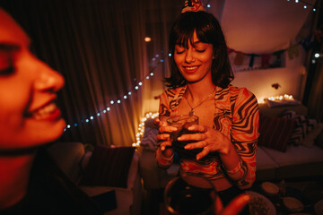 Poster - A young woman joyfully celebrating her birthday with a friend in a warmly decorated room. The festive atmosphere is highlighted by twinkling lights and colorful decorations, setting a cheerful mood.