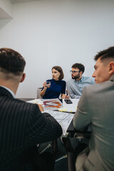 Canvas Print - A group of diverse business employees are analyzing and discussing project plans together at a conference table. They are engaged in teamwork and creative brainstorming to achieve business goals.