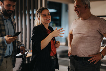 Wall Mural - A group of diverse colleagues engaging in a relaxed conversation in their modern office setting. The image captures a candid moment of laughter and connection among team members.