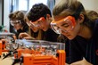 © HO - A group of young engineers testing a prototype machine in a laboratory setting, wearing safety goggles and engaging hands-on with tools and instruments.