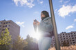 © Johnér - Low angle view of woman using mobile phone and leaning on pole against sky