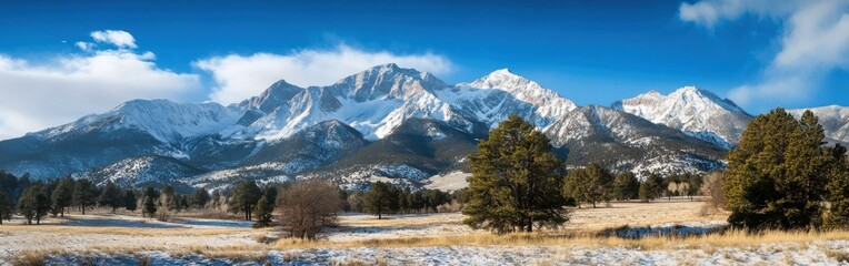 Poster - Snow-covered mountain range under a clear blue sky with scattered clouds during daylight