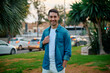 © Cavan Images - Young man smiles in a park while casually dressed during sunset