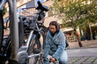 © Johnér - Young woman locking bicycle on footpath