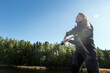 © Johnér - Low angle view of mid adult woman fishing at lake on sunny day