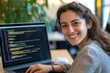 © romanets_v - Hispanic female young adult smiling while coding on laptop in office environment
